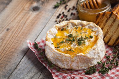 Gerçek bir Camembert kekik, bal ve eski ahşap rustik masa üzerinde kızarmış ekmek ile üzerinden. Yumuşak peynir bir ahşap zemin üzerinde. Üstten Görünüm