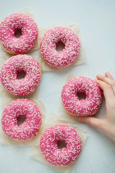 Donut. Sweet icing sugar food. Dessert colorful snack. Glazed sprinkles. Treat from delicious pastry breakfast. Bakery cake. Doughnut with frosting. A woman's hand takes a donut. Top view — Stock Photo, Image