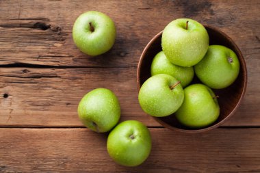 Eski rustik masa ahşap bir kasede olgun yeşil elma. Ahşap arka plan üzerinde yararlı meyve. Kopya alanı ile Üstten Görünüm