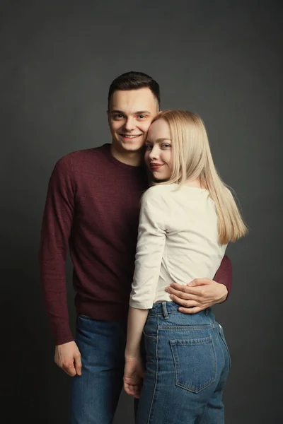 Porträtt av ett vackert ungt par i kärlek poserar på studio över mörk bakgrund — Stockfoto