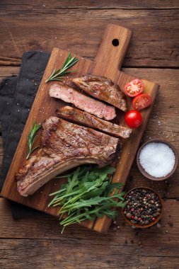 Izgara kovboy sığır eti biftek, otlar ve baharatlar rustik ahşap arka plan üzerinde. Üstten Görünüm