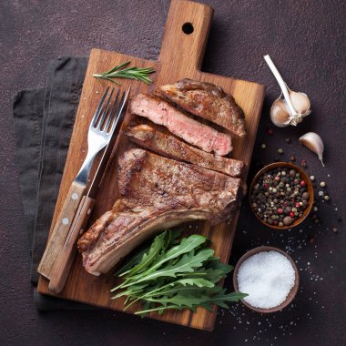 Izgara kovboy sığır eti biftek, otlar ve baharatlar karanlık bir taş zemin üzerine. Üstten Görünüm