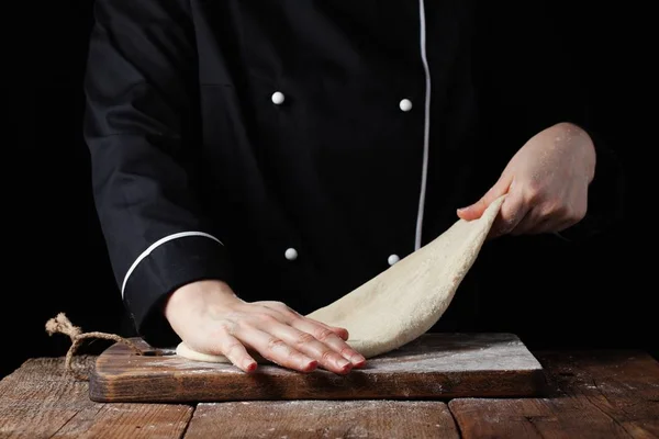 Шеф-повар месит тесто, делает тесто женскими руками в пекарне на черном фоне — стоковое фото