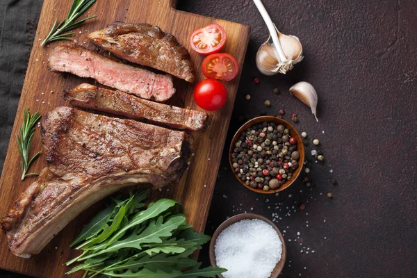 Bife grelhado de vaca cowboy, ervas e especiarias em uma pedra escura de volta — Fotografia de Stock