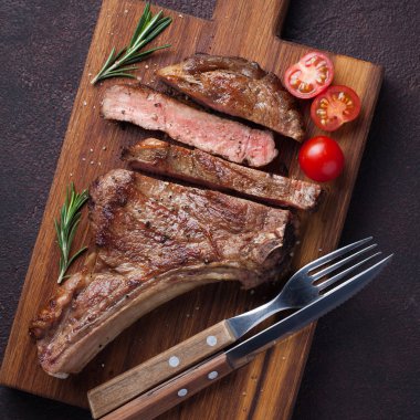 Izgara kovboy sığır eti biftek, otlar ve baharatlar karanlık bir taş zemin üzerine. Üstten Görünüm