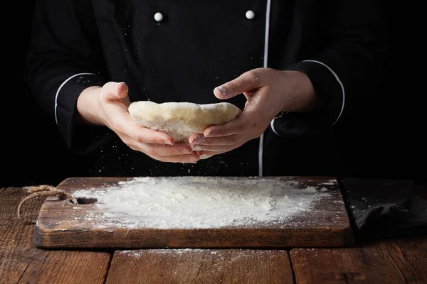 Chef hembra sosteniendo masa de levadura en sus manos sobre fondo negro — Foto de Stock