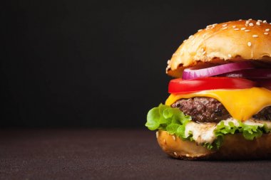 Marul, peynir, soğan ve domates kopya alanı ile karanlık bir arka plan üzerinde lezzetli taze ev yapımı hamburger Close-Up