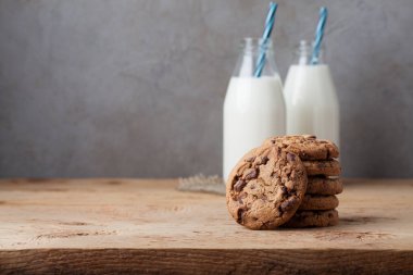 İki şişe süt ve Çikolata parçalı kurabiye kopya alanı ile koyu arka plan üzerinde