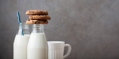 İki şişe süt ve Çikolata parçalı kurabiye kopya alanı ile koyu arka plan üzerinde