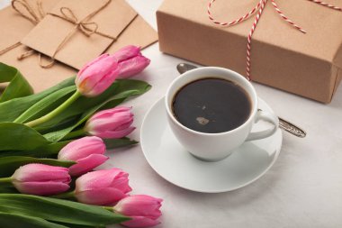 Pembe Laleler, bir fincan kahve ve hafif bir taş zemin üzerine bir hediye. Bahar kavramı