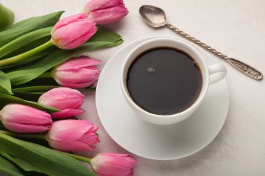 Işık taş zemin üzerine Pembe Lale ile beyaz fincan sade kahve. Üstten Görünüm