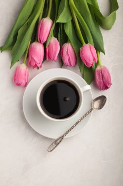 Işık taş zemin üzerine Pembe Lale ile beyaz fincan sade kahve. Kopya alanı ile Üstten Görünüm