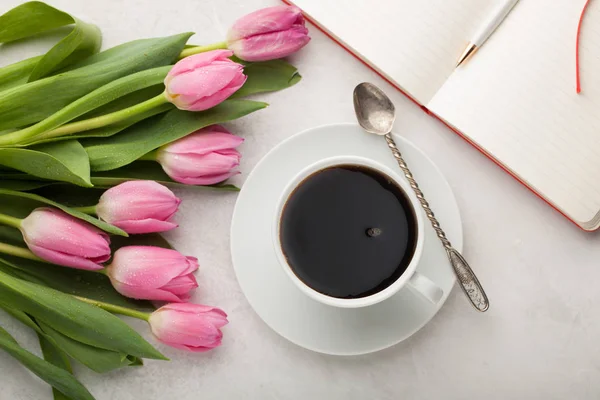 Woman working desk with coffee mug, notebook and spring tulip flowers top view in flat lay style