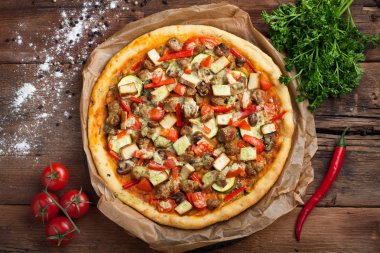 Ev yapımı vejetaryen pizza domates, kabak, biber, mantar ve soya eti eski ahşap masa. Üstten Görünüm