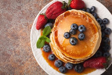 Taze yaban mersini, çilek ve paslı bir arka plan üzerinde akçaağaç şurubu ile yakın çekim lezzetli gözleme. Kopya alanı ile. Üstten Görünüm