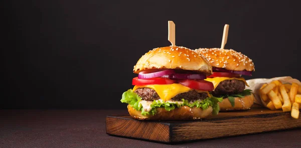 Primer plano de deliciosa hamburguesa casera fresca con lechuga, queso, cebolla y tomate sobre un fondo oscuro con espacio para copiar. concepto de comida rápida y comida chatarra — Foto de Stock