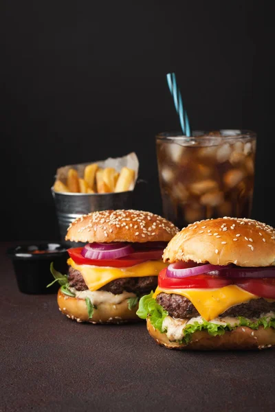 Primer plano de deliciosa hamburguesa casera fresca con lechuga, queso, cebolla, tomate y cola con hielo sobre un fondo oscuro — Foto de Stock