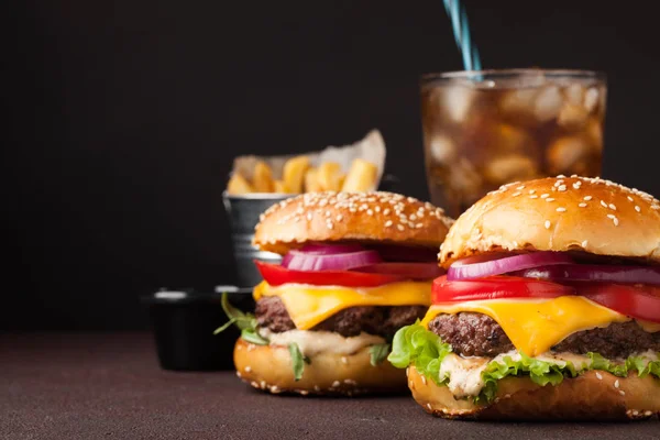 Primer plano de deliciosa hamburguesa casera fresca con lechuga, queso, cebolla, tomate y cola con hielo sobre un fondo oscuro con espacio para copiar — Foto de Stock