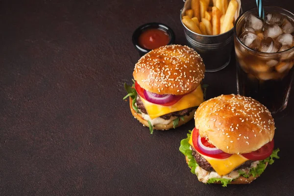 Primer plano de deliciosa hamburguesa casera fresca con lechuga, queso, cebolla, tomate y cola con hielo sobre un fondo oscuro con espacio para copiar — Foto de Stock