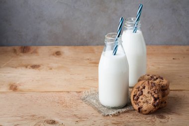 İki şişe süt ve Çikolata parçalı kurabiye kopya alanı ile koyu arka plan üzerinde