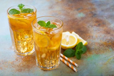 Limon, nane ve uzun boylu gözlük buz ile geleneksel buzlu çay. Eski paslı arka plan üzerinde serin yaz içkiyle iki bardak