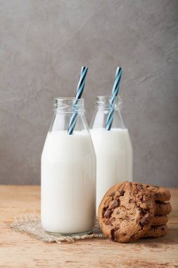 İki şişe süt ve Çikolata parçalı kurabiye kopya alanı ile koyu arka plan üzerinde