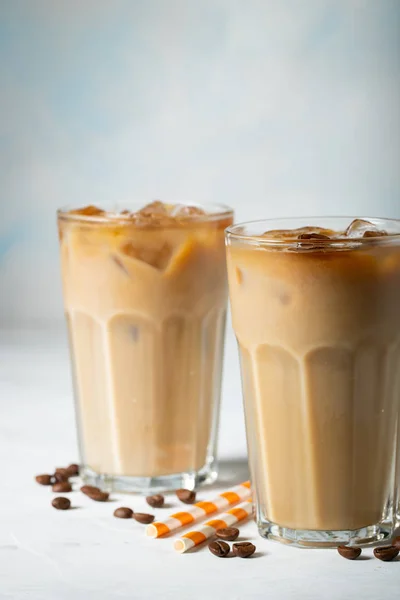Кофе со льдом в высоком стакане со сливками и кофейными зёрнами. Холодный летний напиток на светло-голубом фоне — стоковое фото