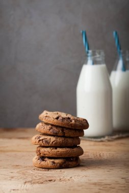 Sütlü çikolata ve süt ahşap bir masa üzerinde iki şişe ile tatlılar yığını