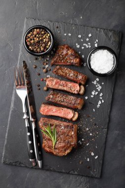 Closeup biftek new York sığır ırkları kara Angus otlar, sarımsak ve bir taş tahta üzerine tereyağı ile yemeye hazır. Bitmiş çanak taş karanlık bir arka plan akşam yemeği için. Üstten Görünüm