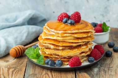 Yakın plan lezzetli krepler, taze yaban mersinli, ahududulu ve ballı.