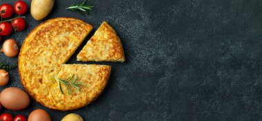 Patates ve soğanlı İspanyol omleti. Siyah beton arka planda tipik İspanyol mutfağı. Tortilla espanola. Kopyalama alanı olan üst görünüm