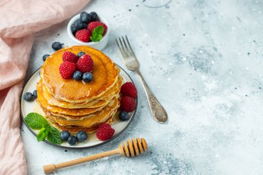 Yakın plan lezzetli krepler, taze yaban mersinli, ahududulu ve ballı. Kopyalama alanı olan üst görünüm
