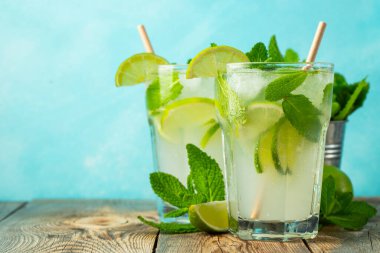 İki ev yapımı limonata ya da mojito kokteyli, limon, nane ve buz küpleri ahşap bir kırsal masada bir bardakta. Taze yaz içkisi. Kopyalama alanı ile.