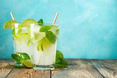 İki ev yapımı limonata ya da mojito kokteyli, limon, nane ve buz küpleri ahşap bir kırsal masada bir bardakta. Taze yaz içkisi. Kopyalama alanı ile.