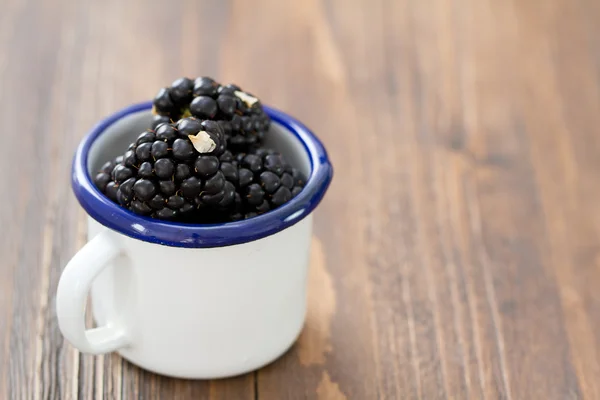 Blackberries in white cup on brown — Stock Photo, Image