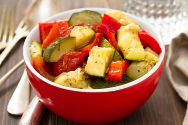 ahşap arka plan üzerinde kırmızı kase pişmiş sebze