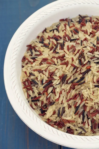 Mavi ahşap arka plan üzerinde beyaz tabakta pirinç