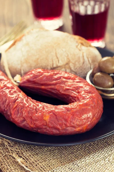 Smoked sausage with bread, olives and red wine — Stock Photo, Image