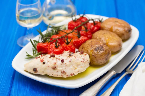 Курица с картошкой и помидорами на блюде — стоковое фото