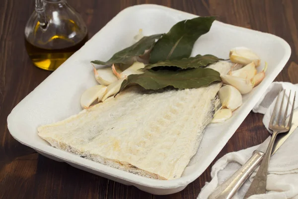 Salted cod fish with bay leaf on dish — Stock Photo, Image