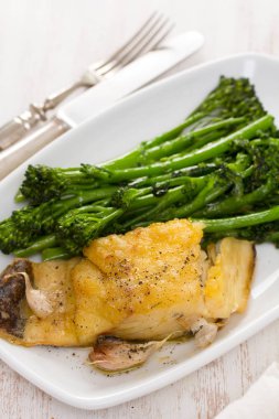 Kızarmış Morina balığı beyaz tabakta yeşillikleri ile