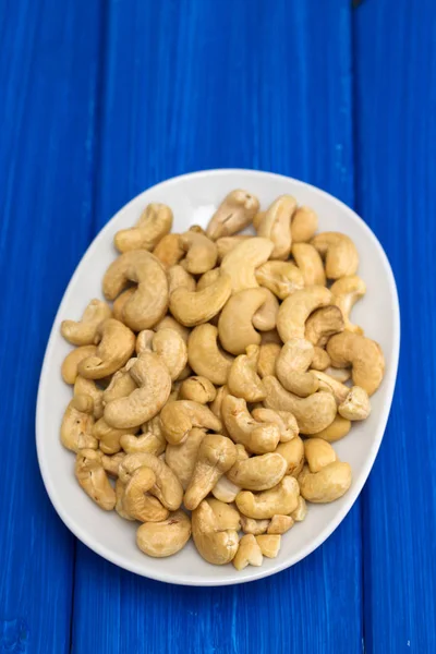 Cashew på hvit tallerken på trebakgrunn – stockfoto