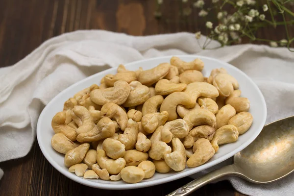 Cashew på hvit tallerken på trebakgrunn – stockfoto