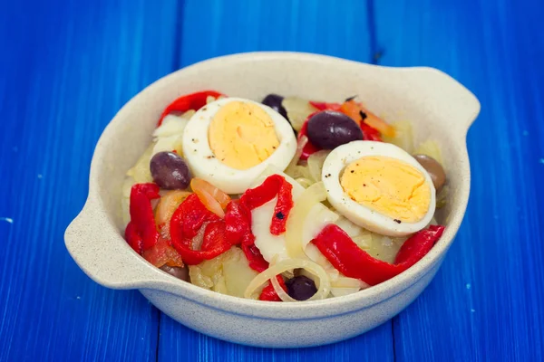 Cod fish with potato, red pepper, egg and olives on dish — Stock Photo, Image