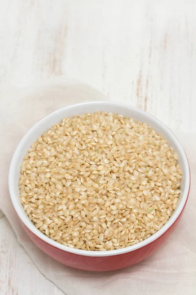 Raw rice in red bowl on wooden background — Stock Photo, Image