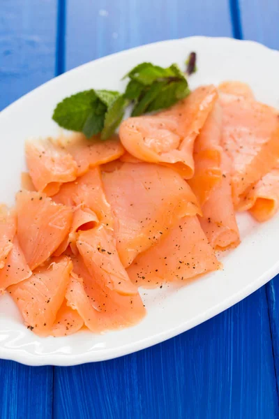 Smoked salmon on white plate on wooden background — Stock Photo, Image