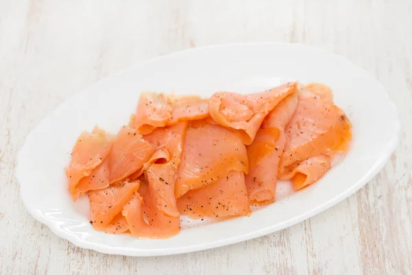 Smoked salmon on white plate on wooden background — Stock Photo, Image