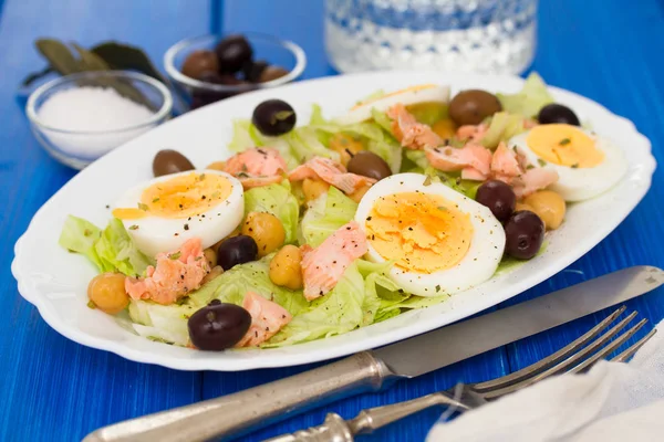 Salad with salmon, eggs and olives on white dish — Stock Photo, Image