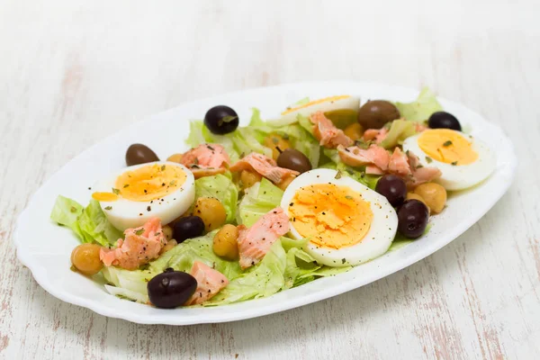 Salada com salmão, ovos e azeitonas em prato branco — Fotografia de Stock