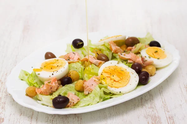 Salad with salmon, eggs and olives on white dish — Stock Photo, Image